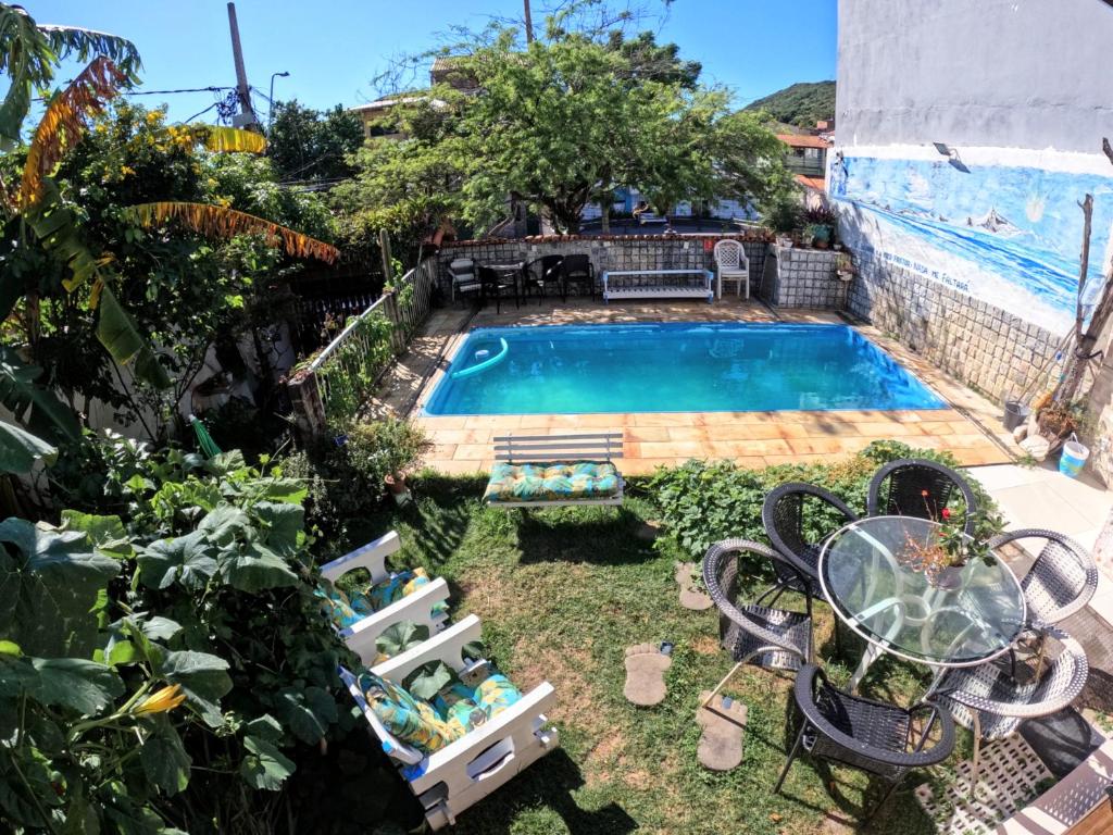 a pool in a yard with chairs and a table at Hostel Paraíso in Arraial do Cabo