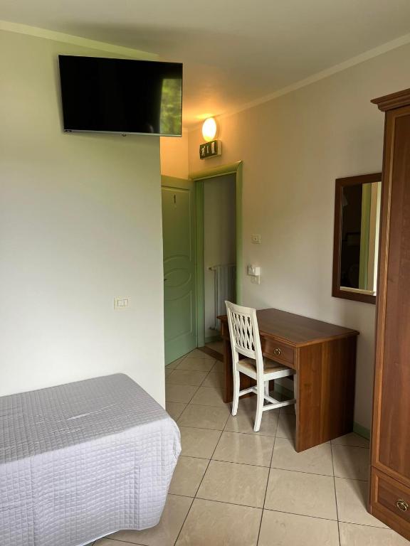a bedroom with a bed and a desk and a television at Foresteria affittacamere in Franciacorta La Pulcinella in Monticelli Brusati