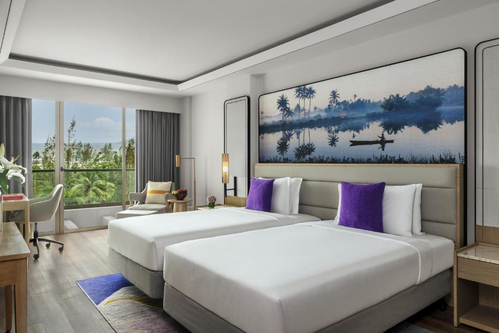 2 camas en una habitación de hotel con almohadas moradas en Vivanta Goa, Miramar en Panaji