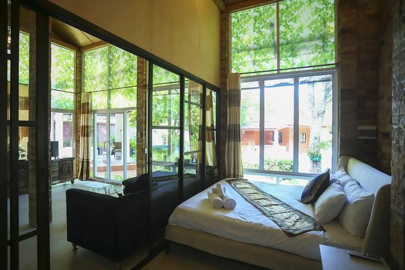 - une chambre avec un lit et une grande fenêtre dans l'établissement พลาบุรี รีสอร์ท, à Ban Phala