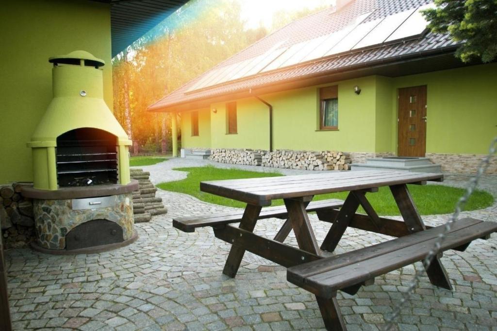 - une table de pique-nique et une cheminée en face du bâtiment dans l'établissement Charmantes Ferienhaus in Zieleniewo mit Garten und Grill und Nah am Strand, à Zieleniewo