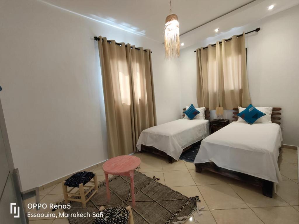 1 Schlafzimmer mit 2 Betten, einem Tisch und einem Stuhl in der Unterkunft Villa Tazerzit comfort et hospitalité in Essaouira