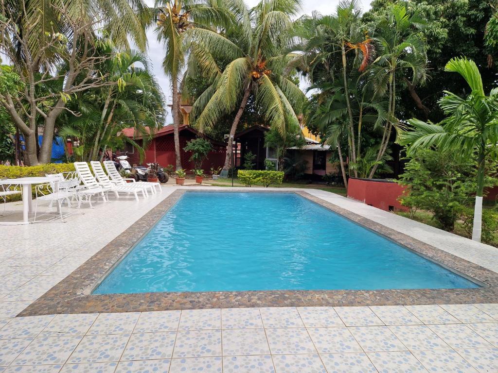 a swimming pool in a resort with chairs and trees at Bungalow chez Mouch Nosy-Be 2 in Nosy Be