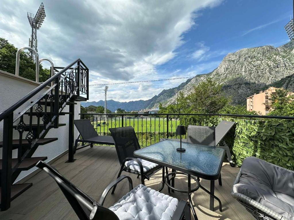 uma varanda com mesa, cadeiras e montanhas em Sunshine Apartment with Private Pool and Parking em Kotor