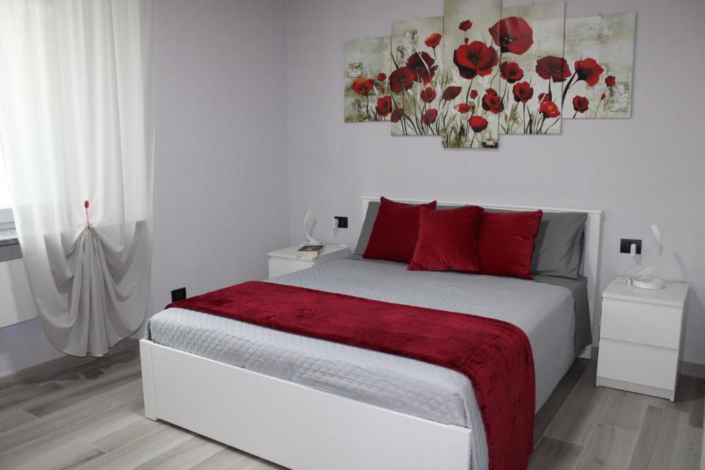 a white bedroom with a bed with red pillows at La Luna Blu Malpensa appartamento Papaveri in Somma Lombardo