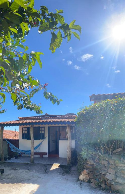 une maison avec un hamac en face de celle-ci dans l'établissement Casinha colibri, à Conceição da Ibitipoca