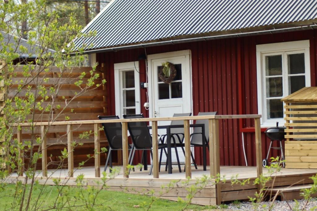 eine kleine rote Kabine mit einer Terrasse und Stühlen in der Unterkunft Rosa's stuga 
