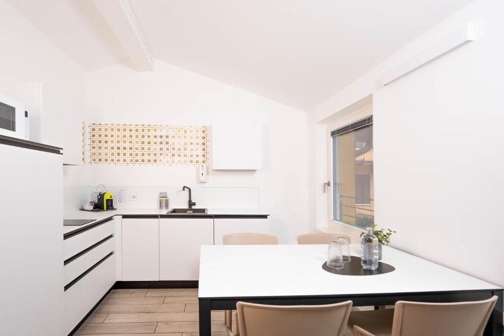 - une cuisine blanche avec une table et des chaises dans l'établissement CityU - Grazioli 27 Trento Centro con parcheggio privato, à Trente
