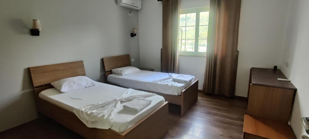 a small room with two beds and a window at Hotel VEAL in Tepelenë