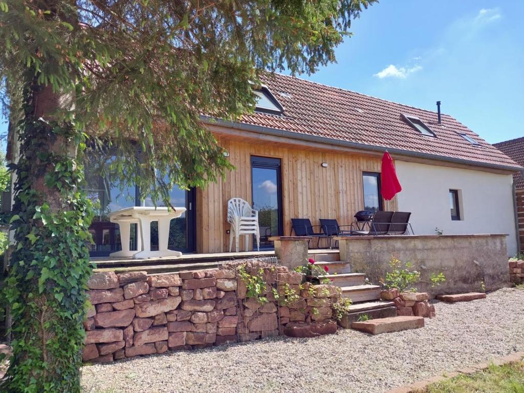 a house with a stone wall and a patio at gite des chênes in Phalsbourg