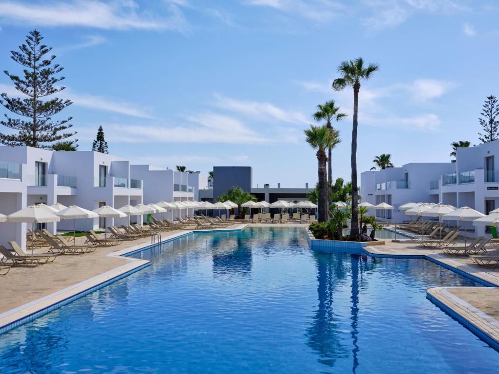 uma piscina com cadeiras e guarda-sóis num resort em Atlantica Panthea Resort em Agia Napa