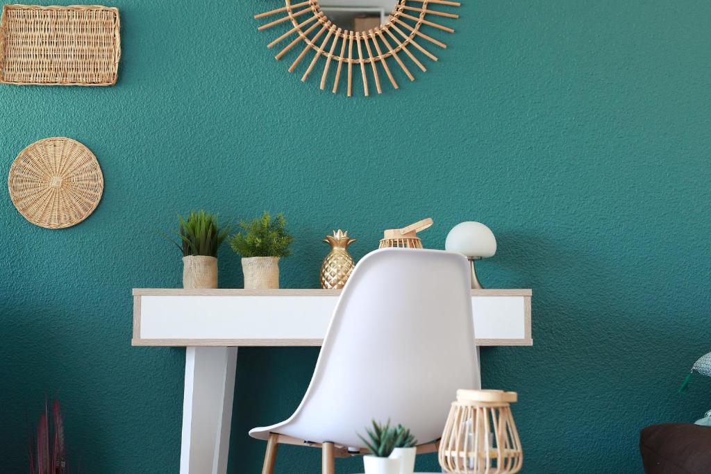 un mur vert avec une étagère blanche et un miroir dans l'établissement Studio le cocon, à La Grande Motte
