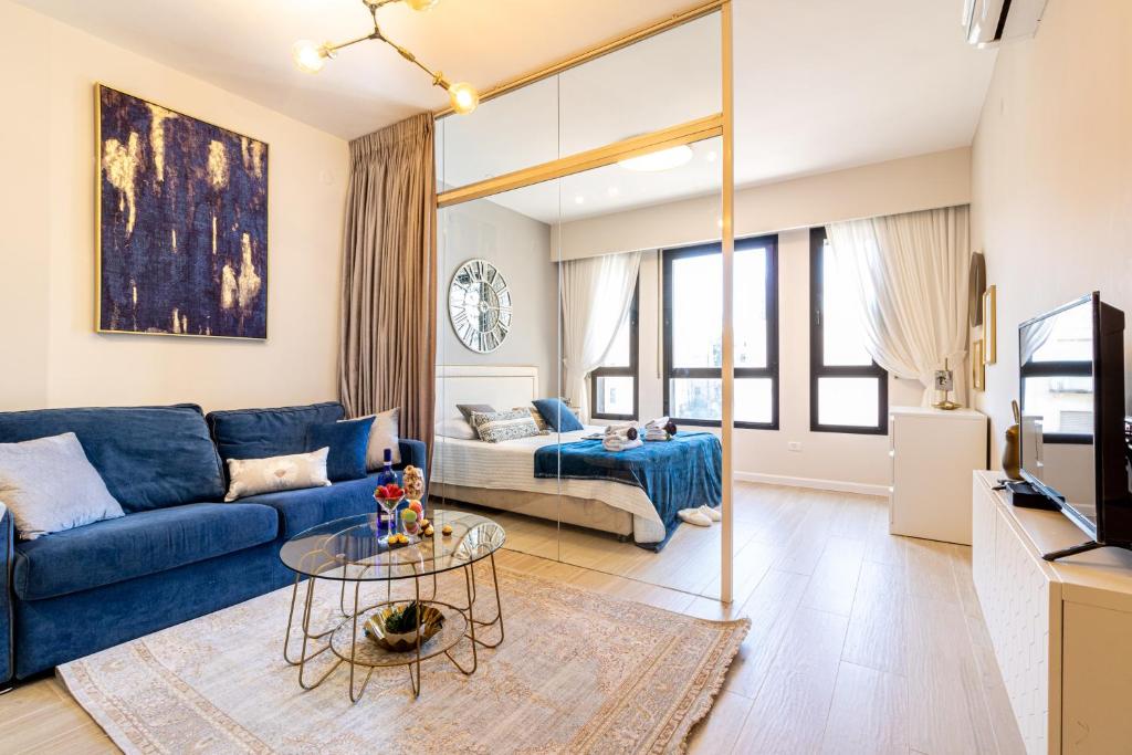 sala de estar con sofá azul y TV en King David Apartment - J&J, en Jerusalén