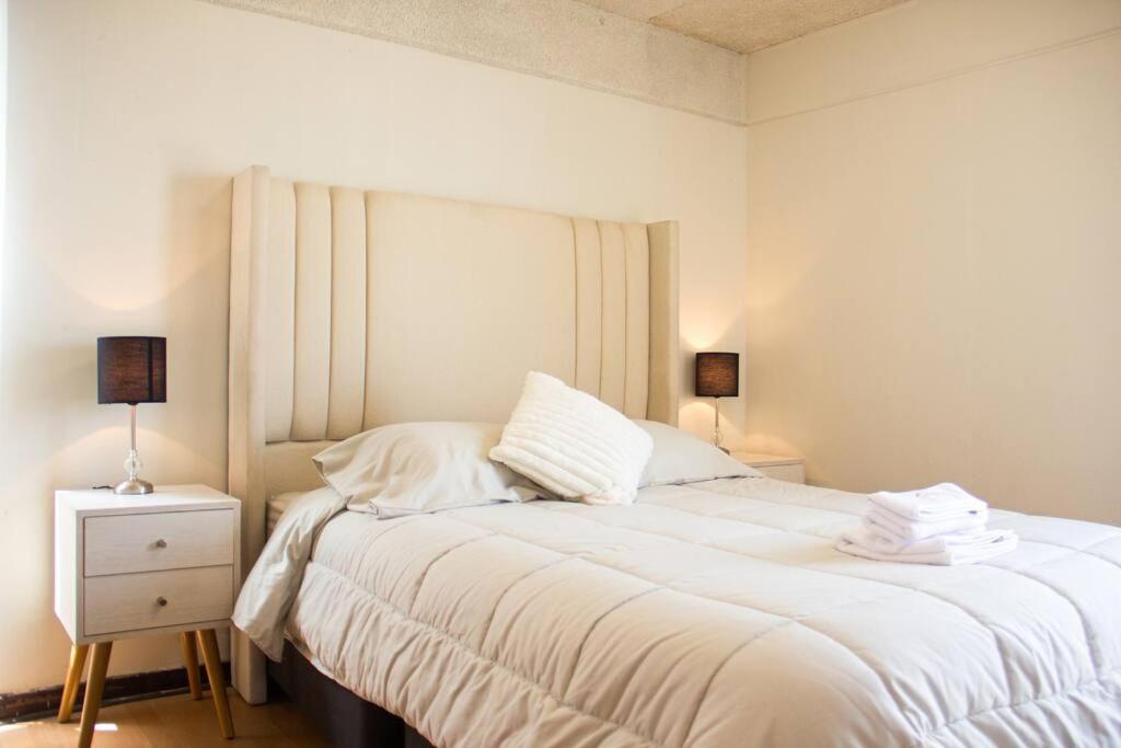 1 dormitorio con 1 cama con sábanas blancas y mesita de noche en Departamento con vista de Lima en San Borja en Lima