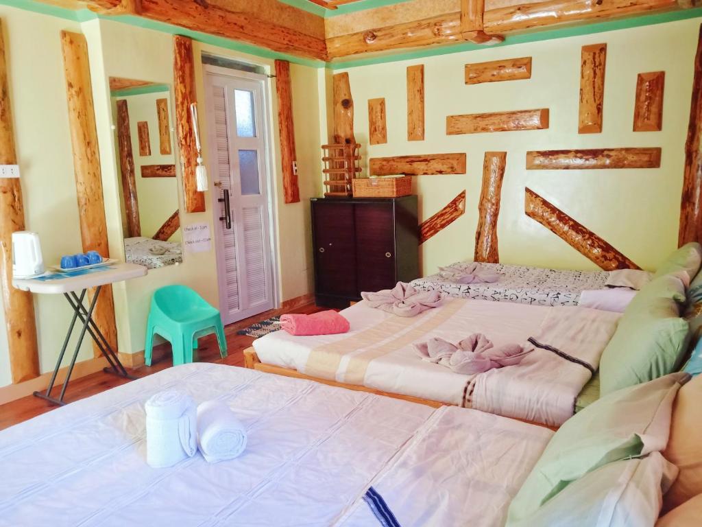a bedroom with two beds and a green chair at Aesthetic Infused with Rustic Vibe Rooms at BOONE'S in Sagada