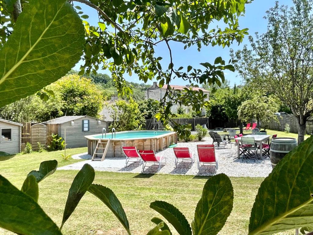 een tuin met een zwembad met stoelen en een tafel bij Les Régniers - 2 gîtes entre vignobles et forêts, proche Dordogne in Eynesse