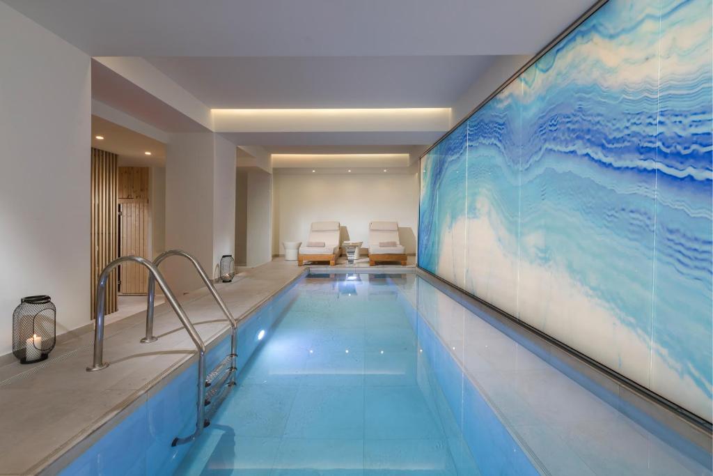 a swimming pool with a large painting on the wall at The Residence Christokopidou Hotel & Spa in Athens