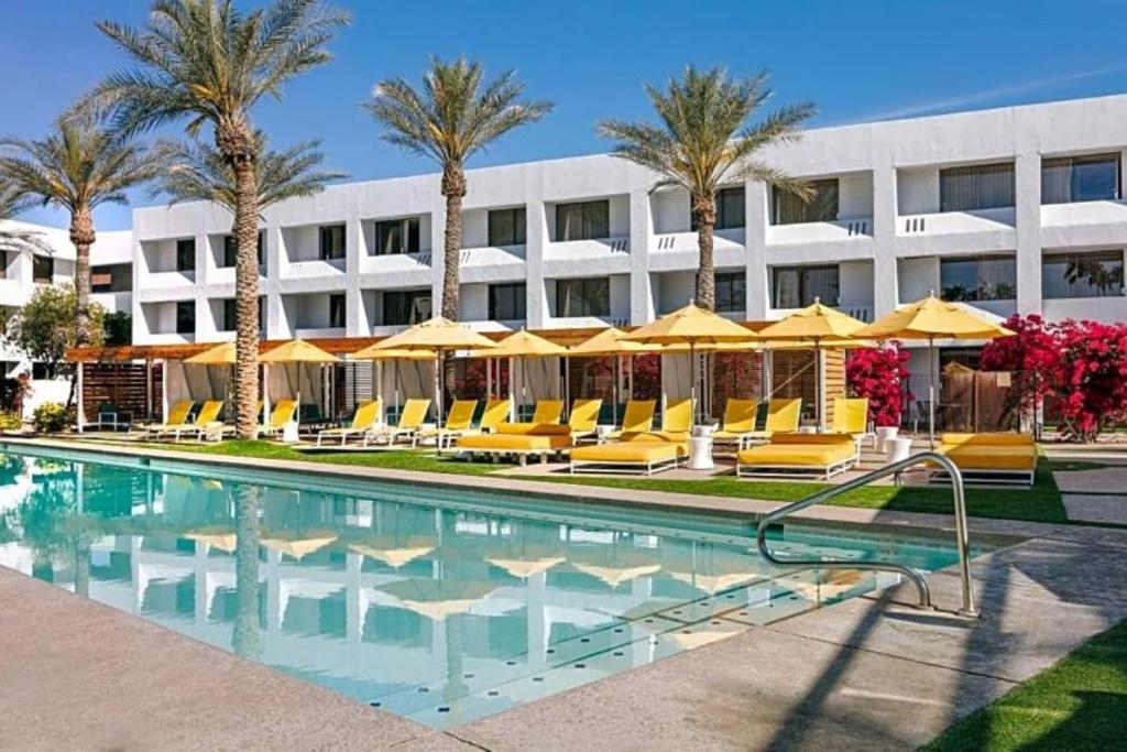 un hotel con una piscina con sillas y sombrillas en The Monarch, en Scottsdale
