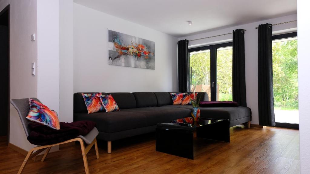 a living room with a black couch and two chairs at Ferienwohnung "Ufer Glück" in Schwerin