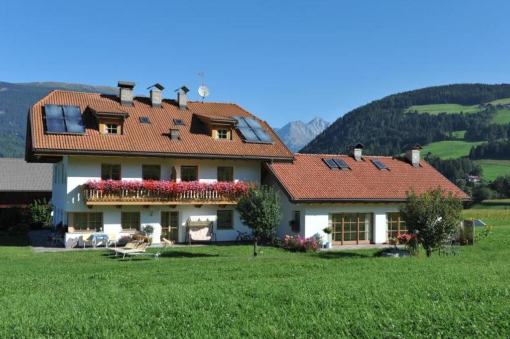 a large house with a green field and mountains at Oberhölzlhof in Valdaora di Sopra