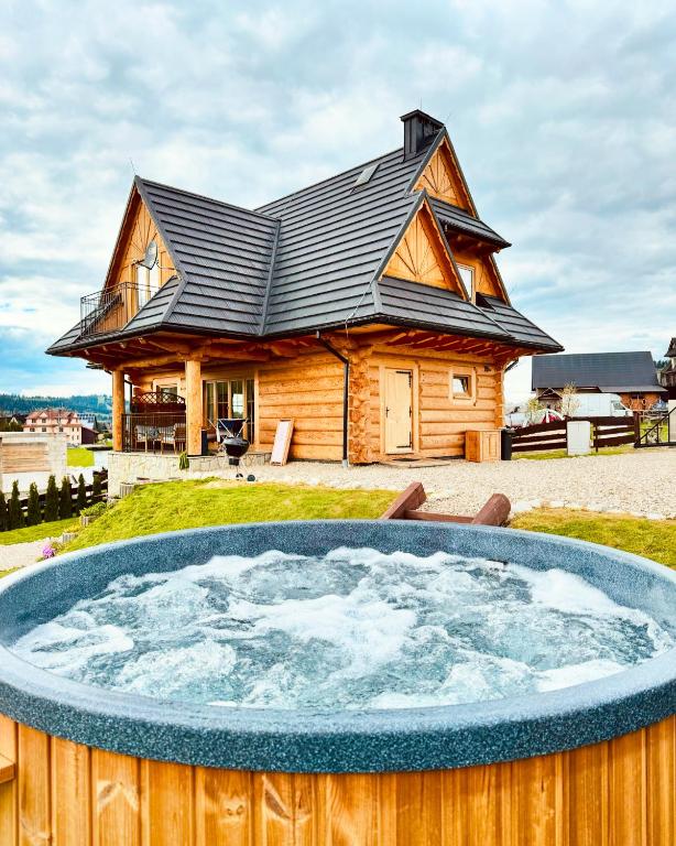 a log cabin with a hot tub in front of a house at Farmerska Chata in Czarna Góra