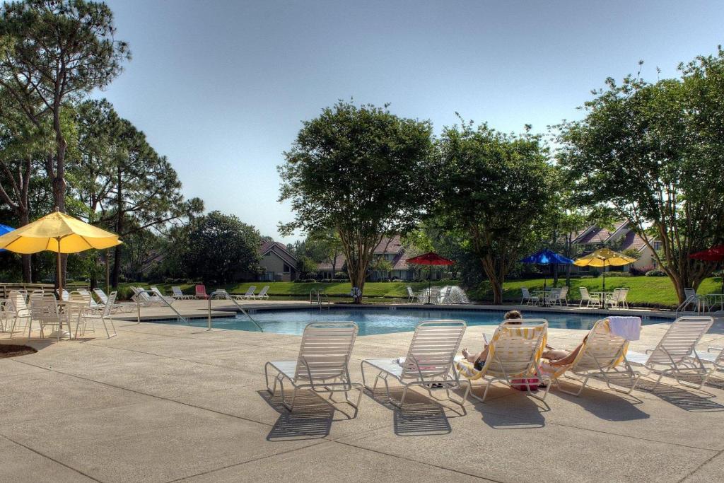 eine Frau, die in Schaukelstühlen neben einem Pool sitzt in der Unterkunft 5191 Beachwalk in Destin