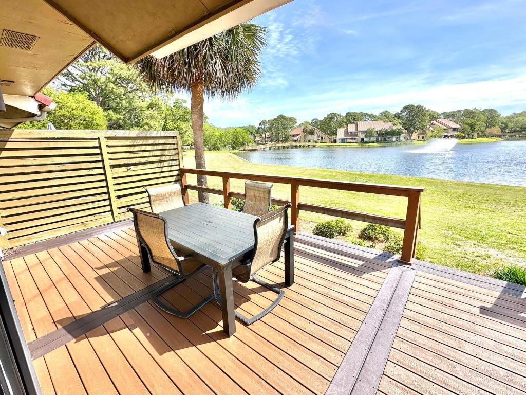 eine Holzterrasse mit einem Tisch, Stühlen und einem See in der Unterkunft 5191 Beachwalk in Destin