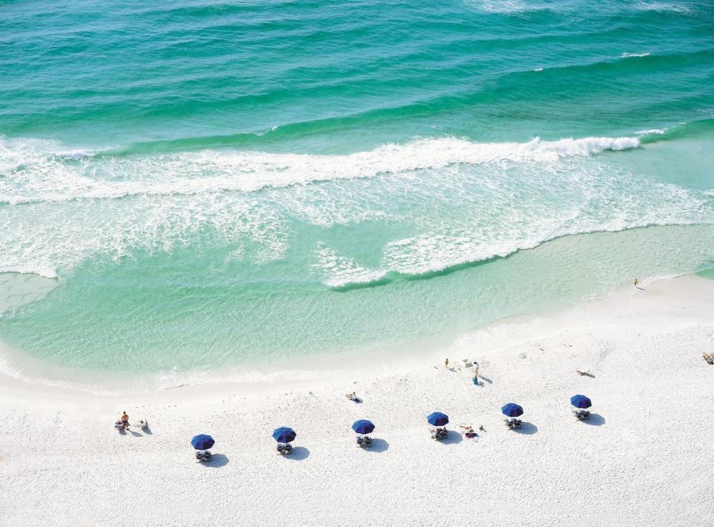 eine Gruppe von Menschen mit Sonnenschirmen an einem Strand in der Unterkunft 5191 Beachwalk in Destin