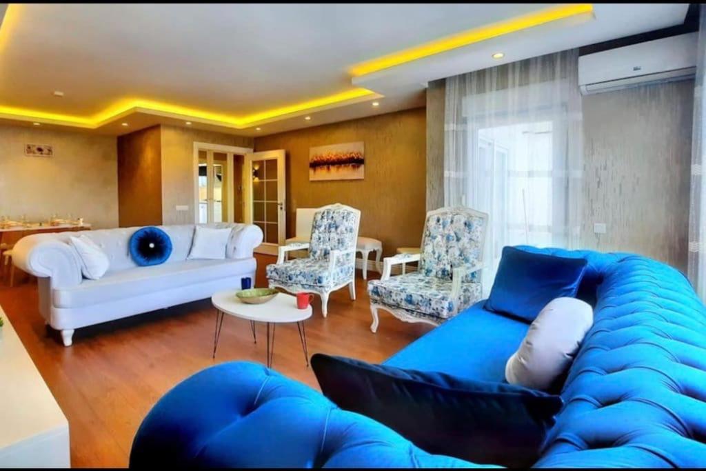 sala de estar con sofá azul y sillas en Mükemmel konum en Antalya