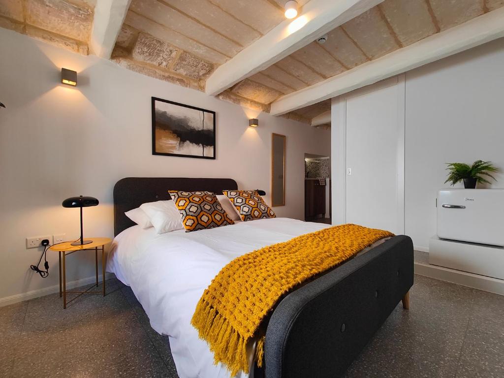 een slaapkamer met een groot bed met een gele deken erop bij Sbejha Boutique Living/ Luqa #2 in Naxxar