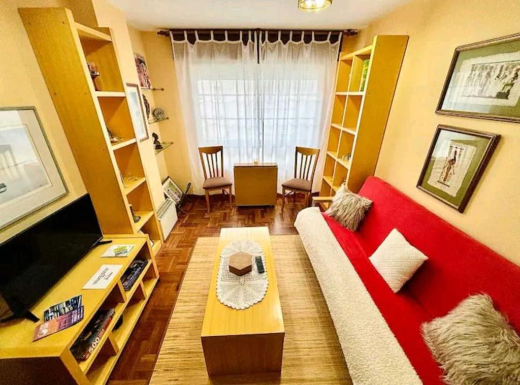 a living room with a red couch and a tv at Holibai, Anduriña, Céntrico Con Parking, Acepta mascotas in Baiona