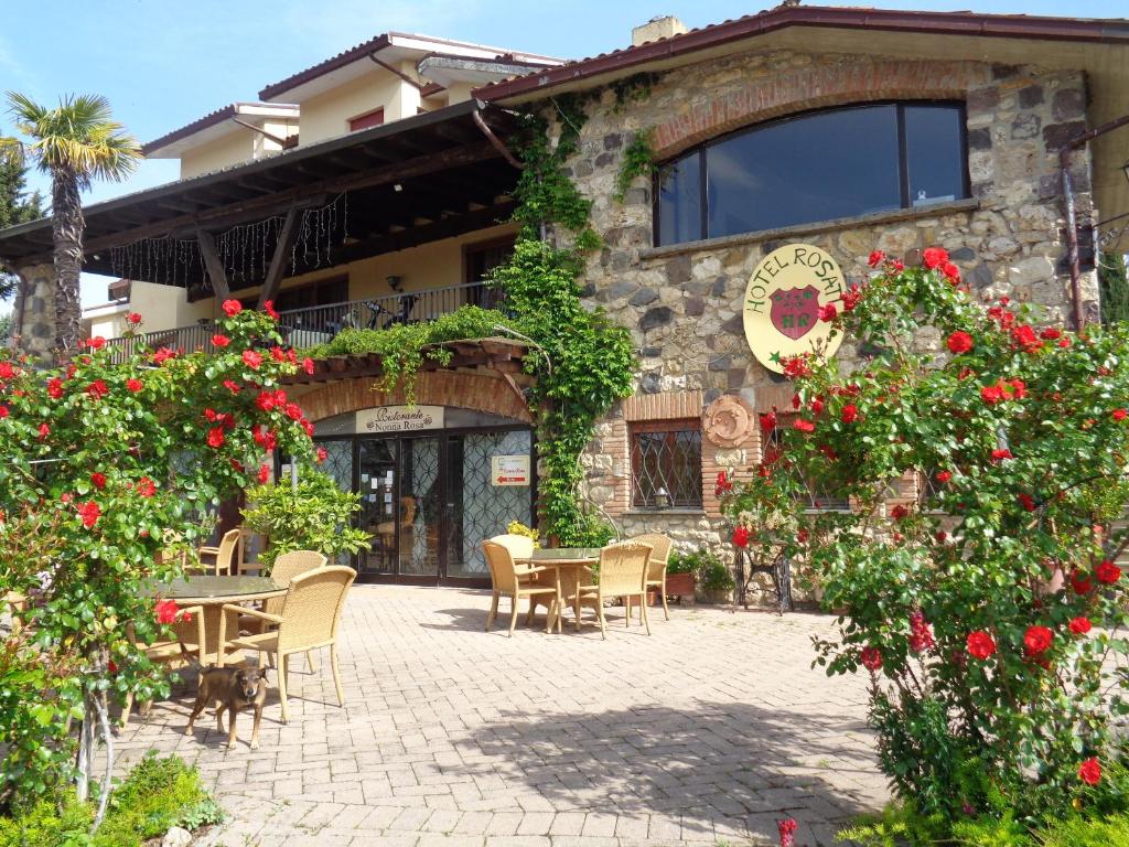 - un bâtiment avec une table, des chaises et des fleurs dans l'établissement Hotel Rosati, à Chiusi