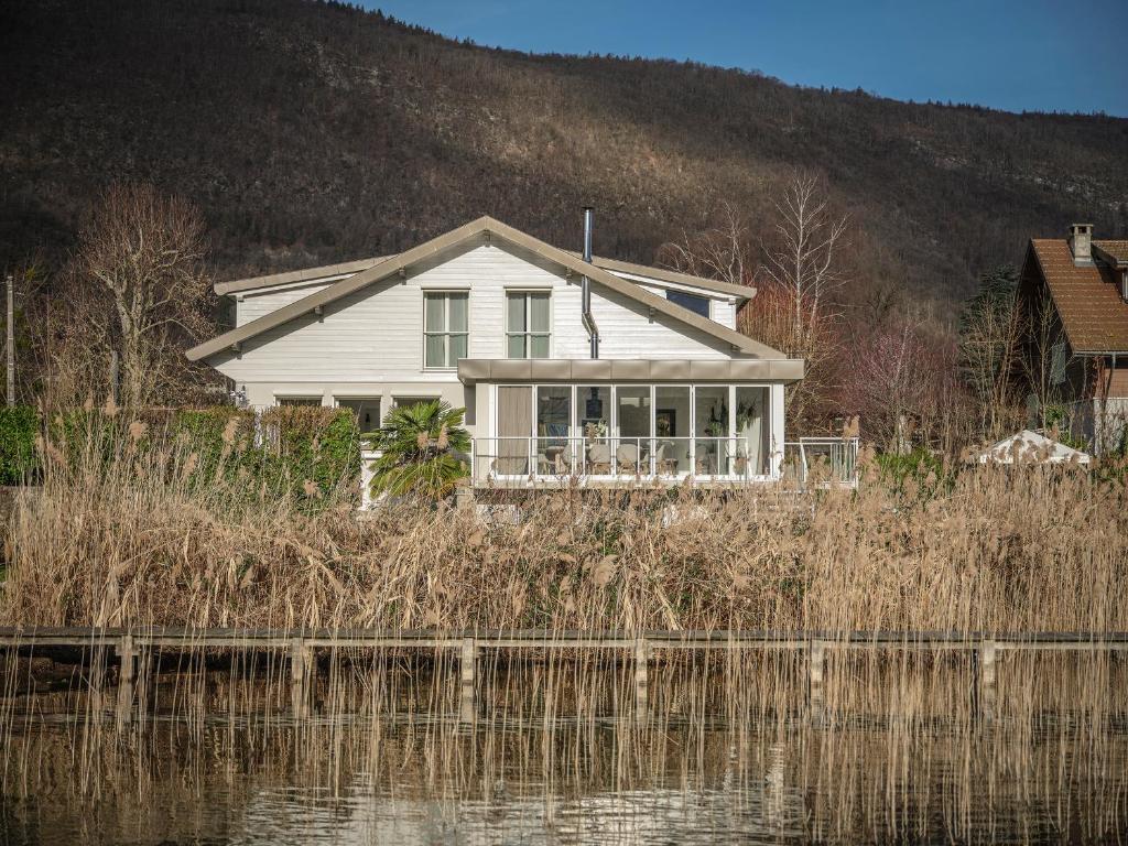 une maison blanche assise à côté d'une nappe d'eau dans l'établissement Venez Chez Vous Villa Aux Premières Loges, à Sévrier