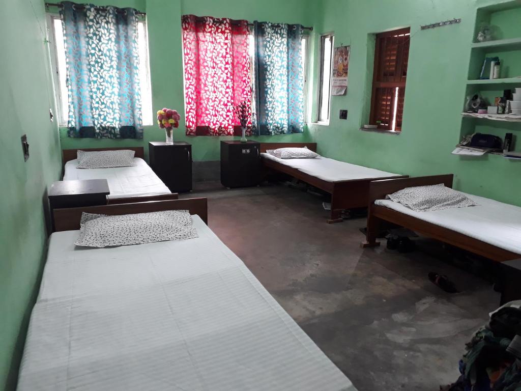 Habitación con 3 camas en una habitación con ventanas en Pushpak Guest House Boys, Near DumDum metro Station, en kolkata
