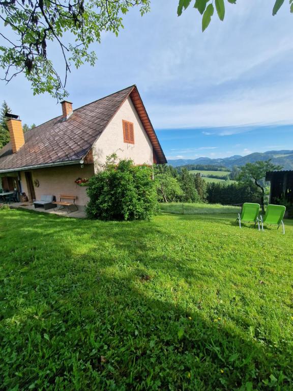 uma casa com duas cadeiras verdes num campo em Natur- & Erlebnis Ferienhaus em Voitsberg