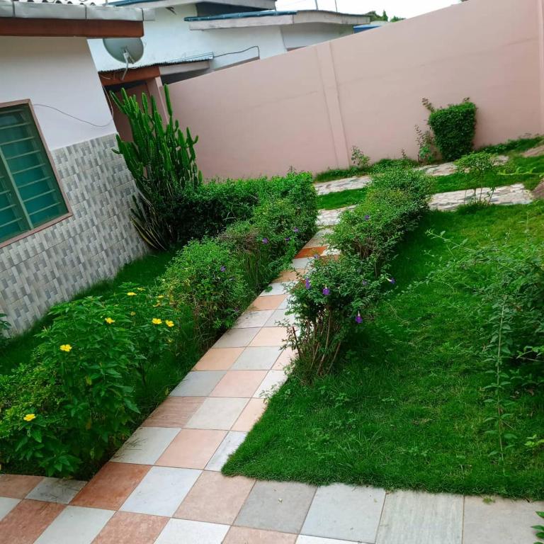 einen Garten mit Gras und Blumen neben einem Gebäude in der Unterkunft Villa meublée Arconville 2 Chambre in Abomey-Calavi