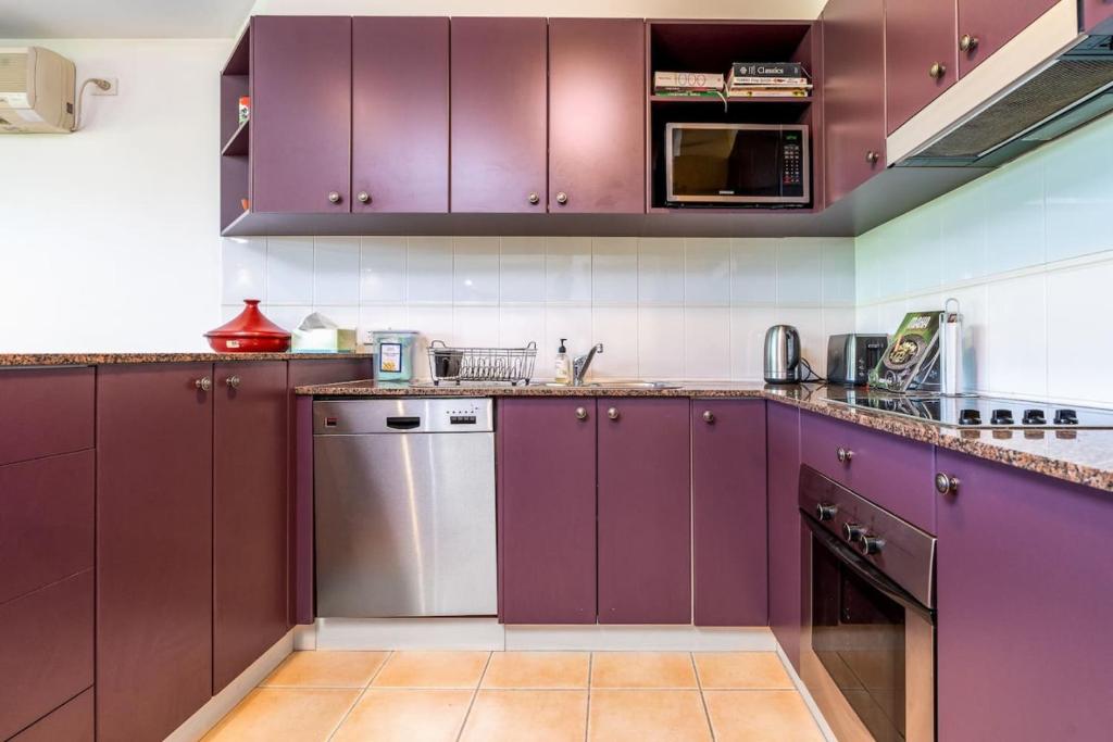 金斯顿2BR 2BA Apt with Dedicated Workspace and Free parking - Hosted by CanStay的厨房配有紫色橱柜和不锈钢洗碗机