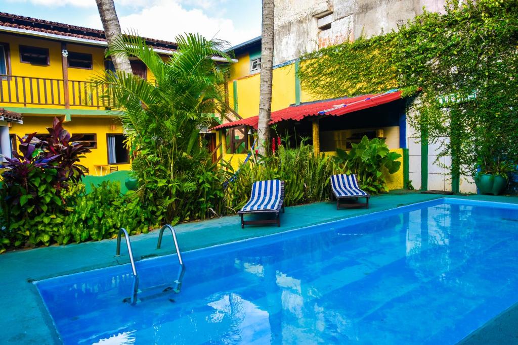 a swimming pool with two chairs next to a building at Hospedagem La Bilbaina in Porto Seguro