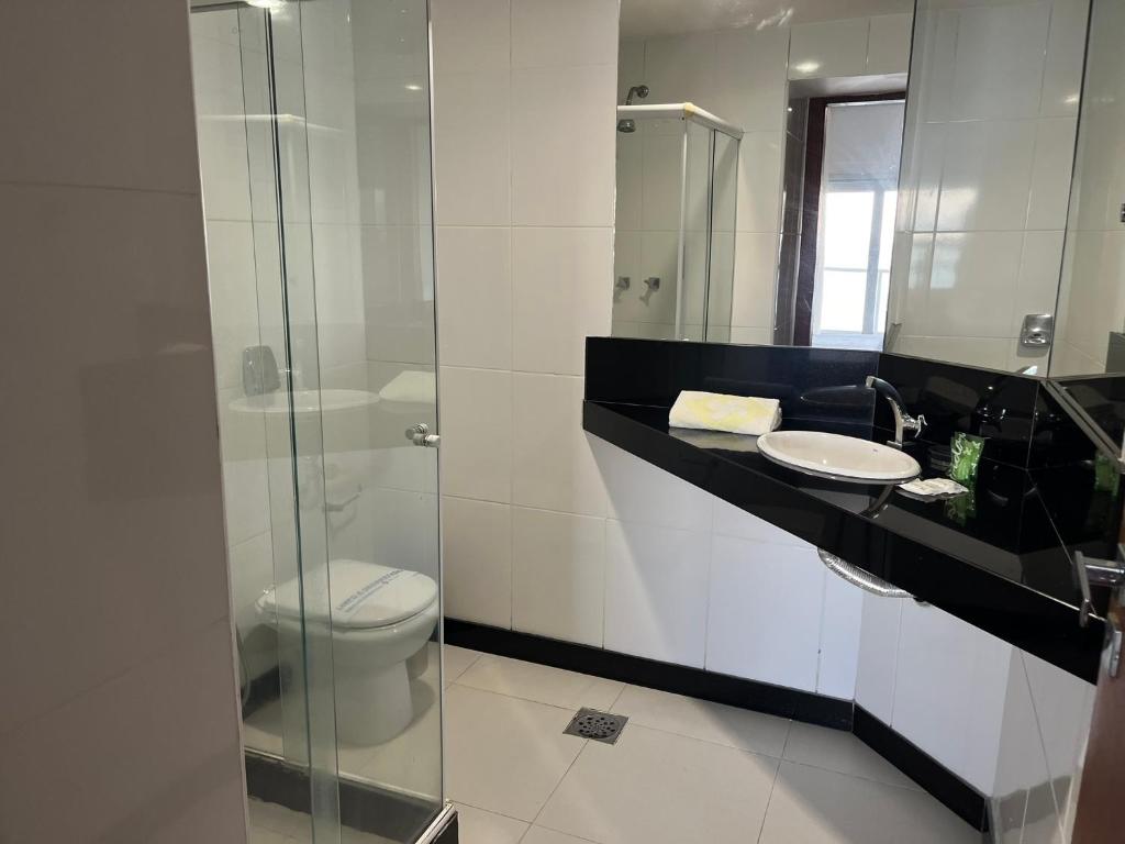 uma casa de banho com um WC e uma cabina de duche em vidro. em Hotel Quatro Estações em Guarapari