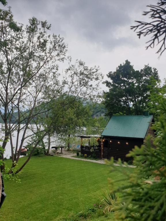 Jajce lake cottage-Plivsko jezero في يايتشه: حظيرة بسقف أخضر بجوار ميدان عشبي