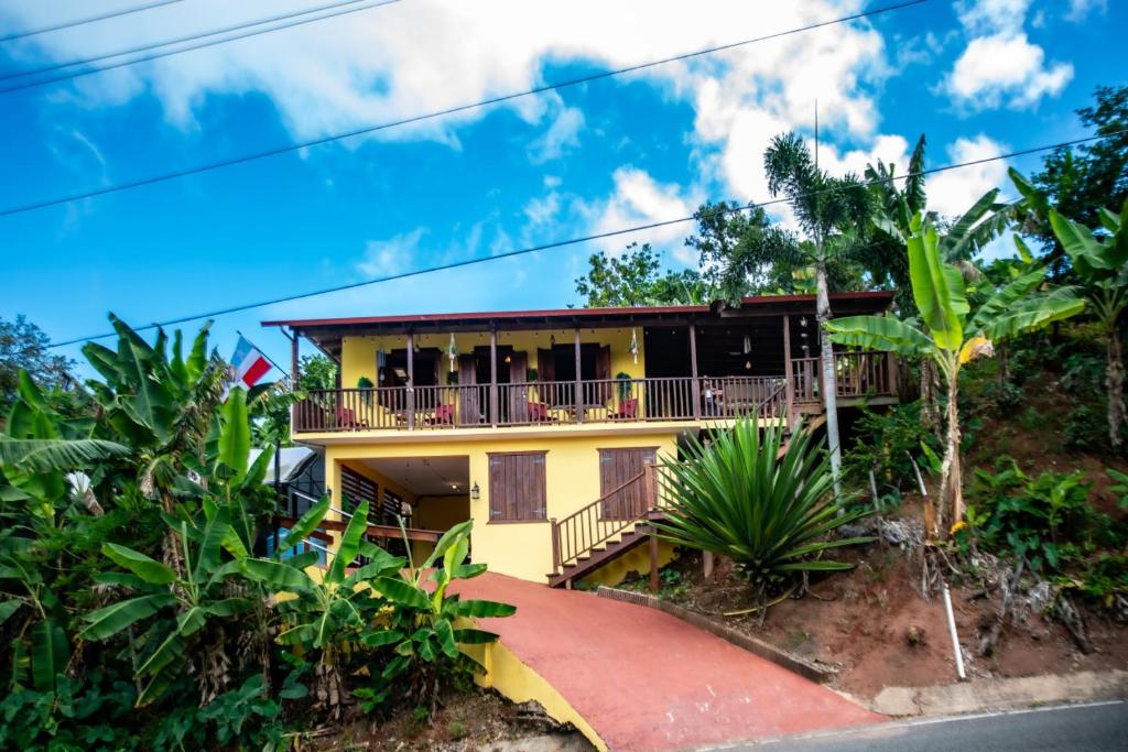 a yellow house with a balcony on a hill at Casa de Campo Vista Hermosa in Lares