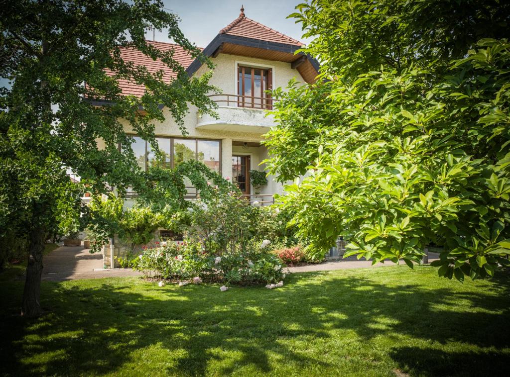 ein Haus mit einem Garten mit Bäumen davor in der Unterkunft Venez Chez Vous - Villa Magnolia in Annecy