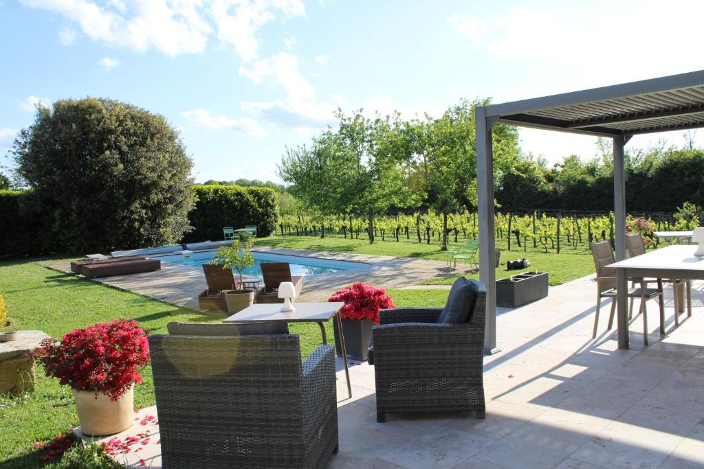 a patio with tables and chairs and a pool at La Vigneraie de Laura in Sainte-Colombe