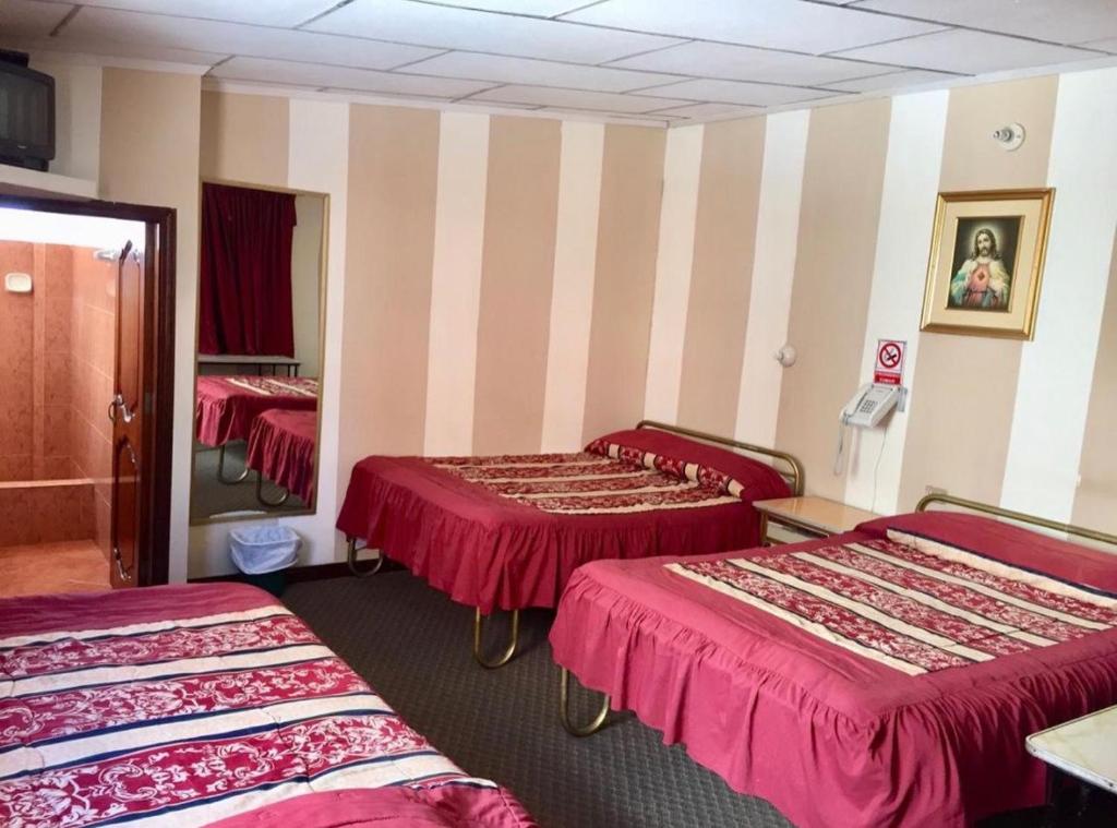 een hotelkamer met 3 bedden en een spiegel bij Hotel Metropolitano in Loja