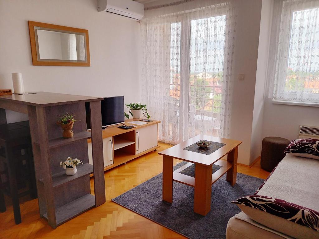 a living room with a tv and a table at Venus Apartman in Brčko