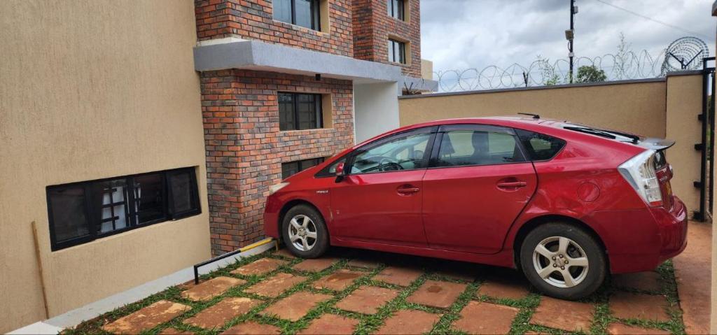 een rode auto geparkeerd voor een gebouw bij Scenic Kigali-View Townhouse in Kigali