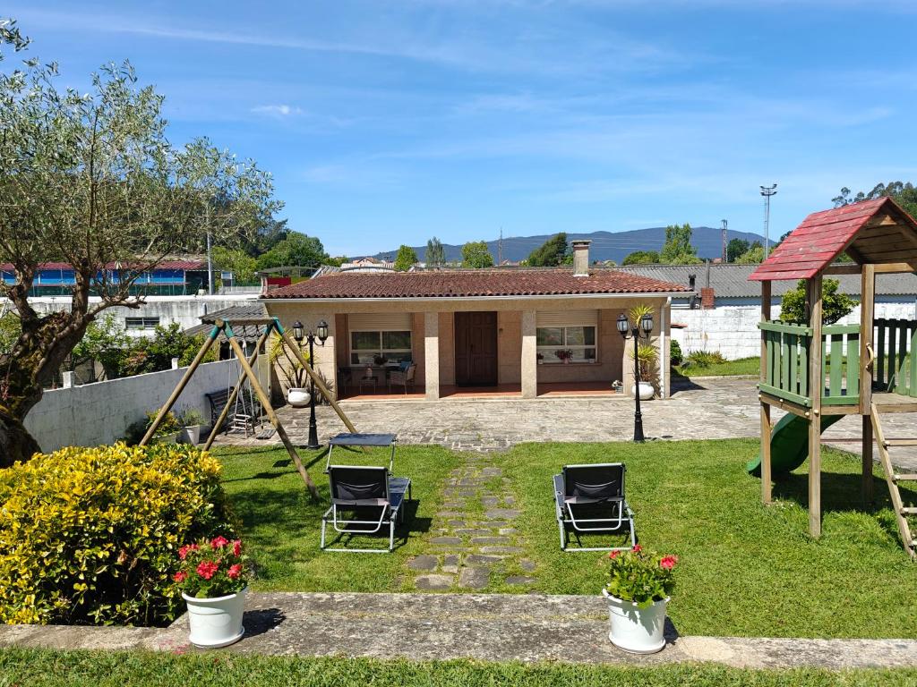 una casa con sillas y un columpio en un patio en A Casa do Choco, en Redondela