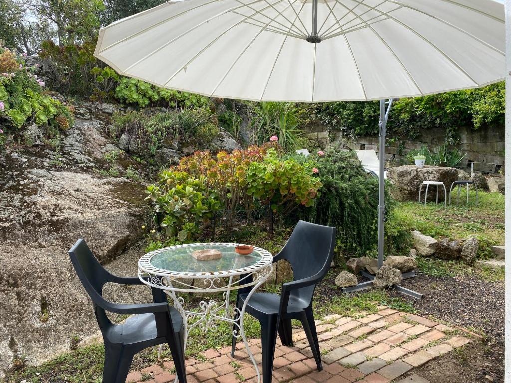 a table and two chairs and an umbrella at chez Béatrice in Porto-Vecchio
