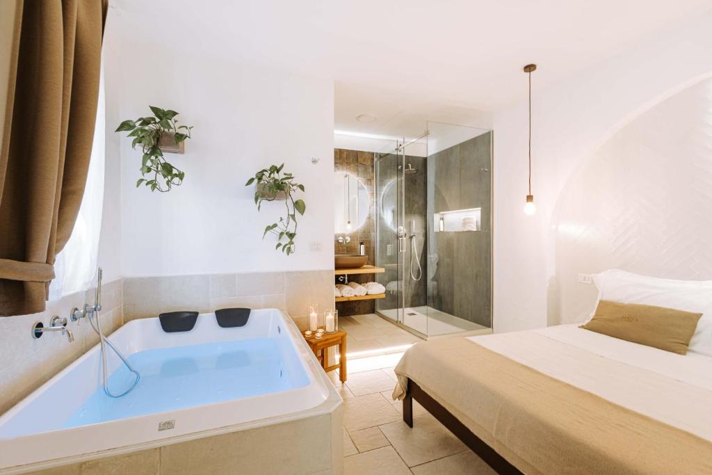 Dirium - exclusive rooms في مونوبولي: حمام مع حوض استحمام بجانب سرير