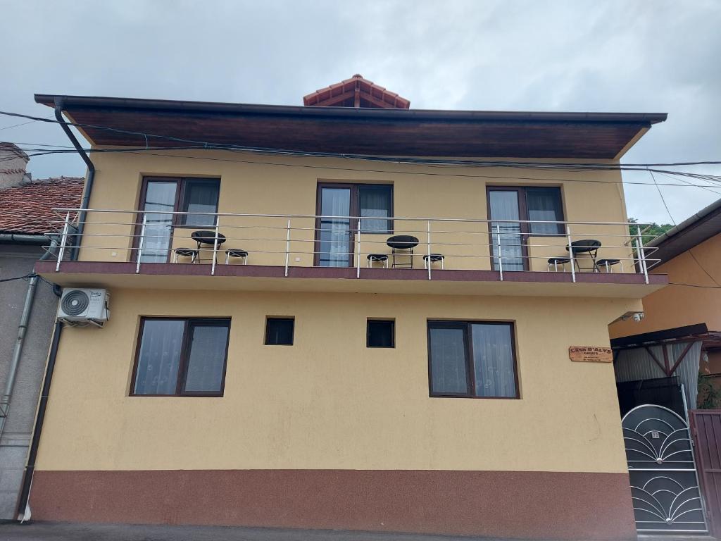 een geel gebouw met een balkon met stoelen erop bij CASA DALYS in Orşova